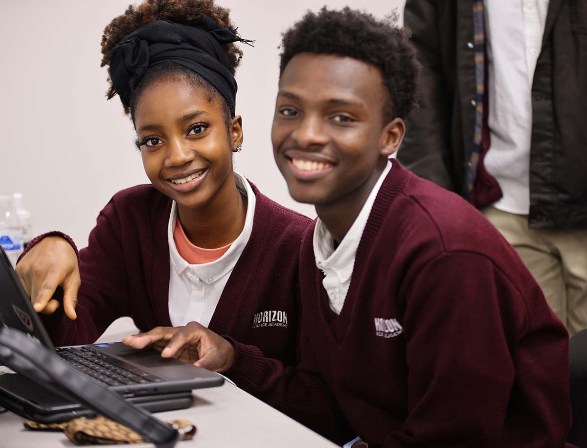 Elementary student smiling and posing together in a classroom.